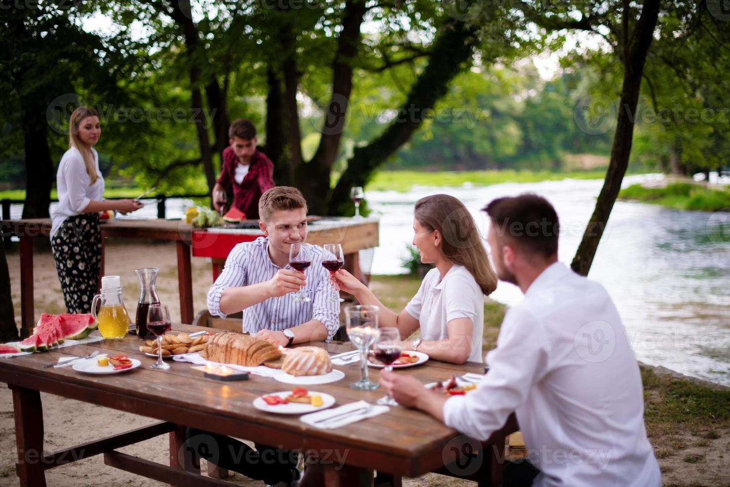 Lycklig vänner har picknick franska middag fest utomhus- foto