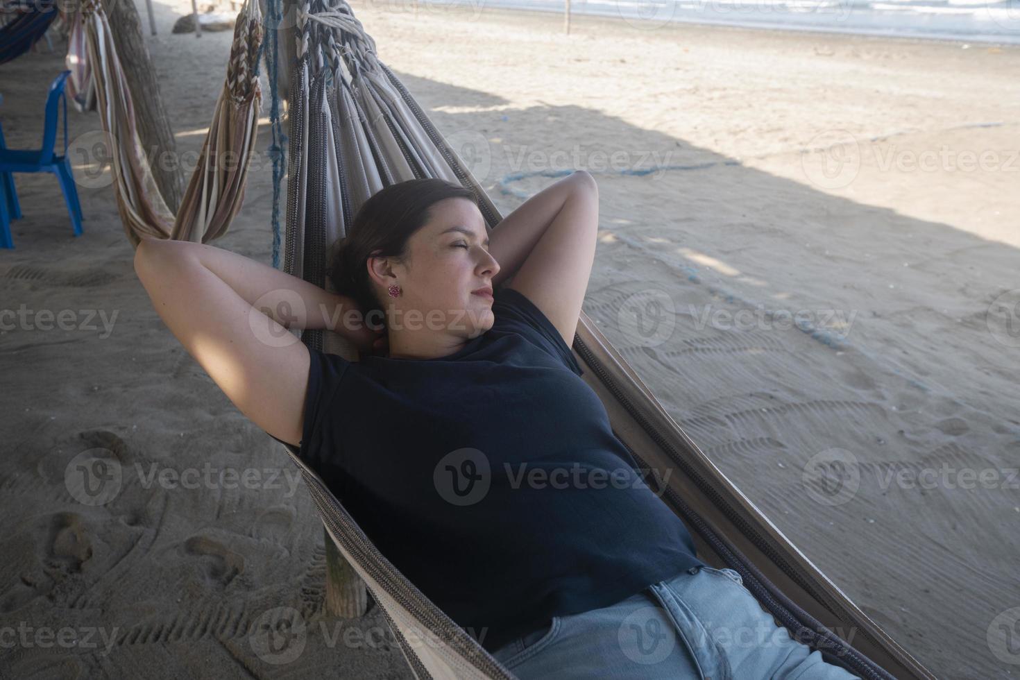 skön latinamerikan ung kvinna vilar i en hängmatta förbi de strand foto