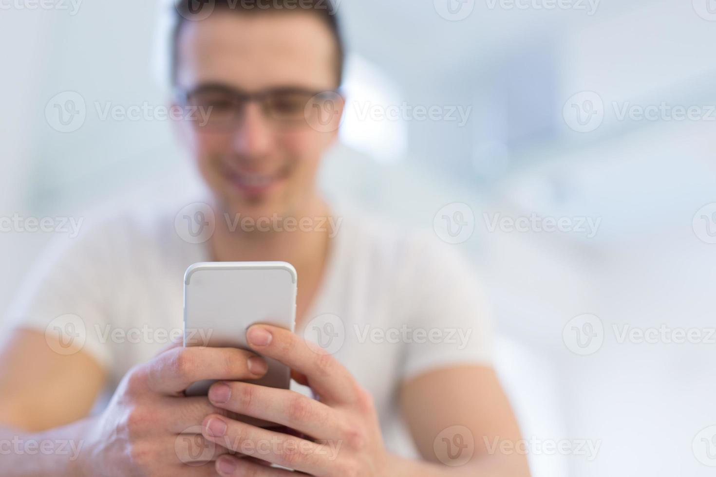 ung man som använder en mobiltelefon hemma foto