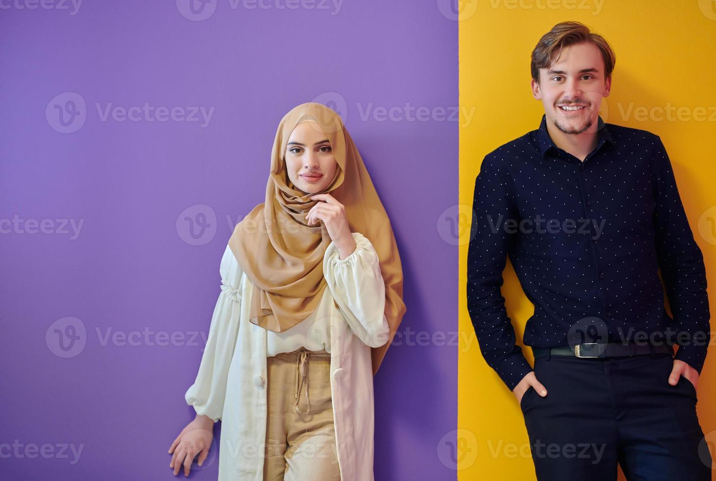 porträtt av Lycklig ung muslim par stående isolerat på färgrik bakgrund foto