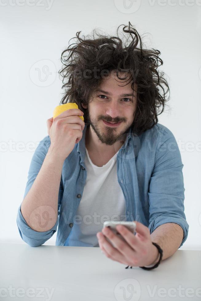 ung man äter äpple och använder sig av en mobil telefon på Hem foto