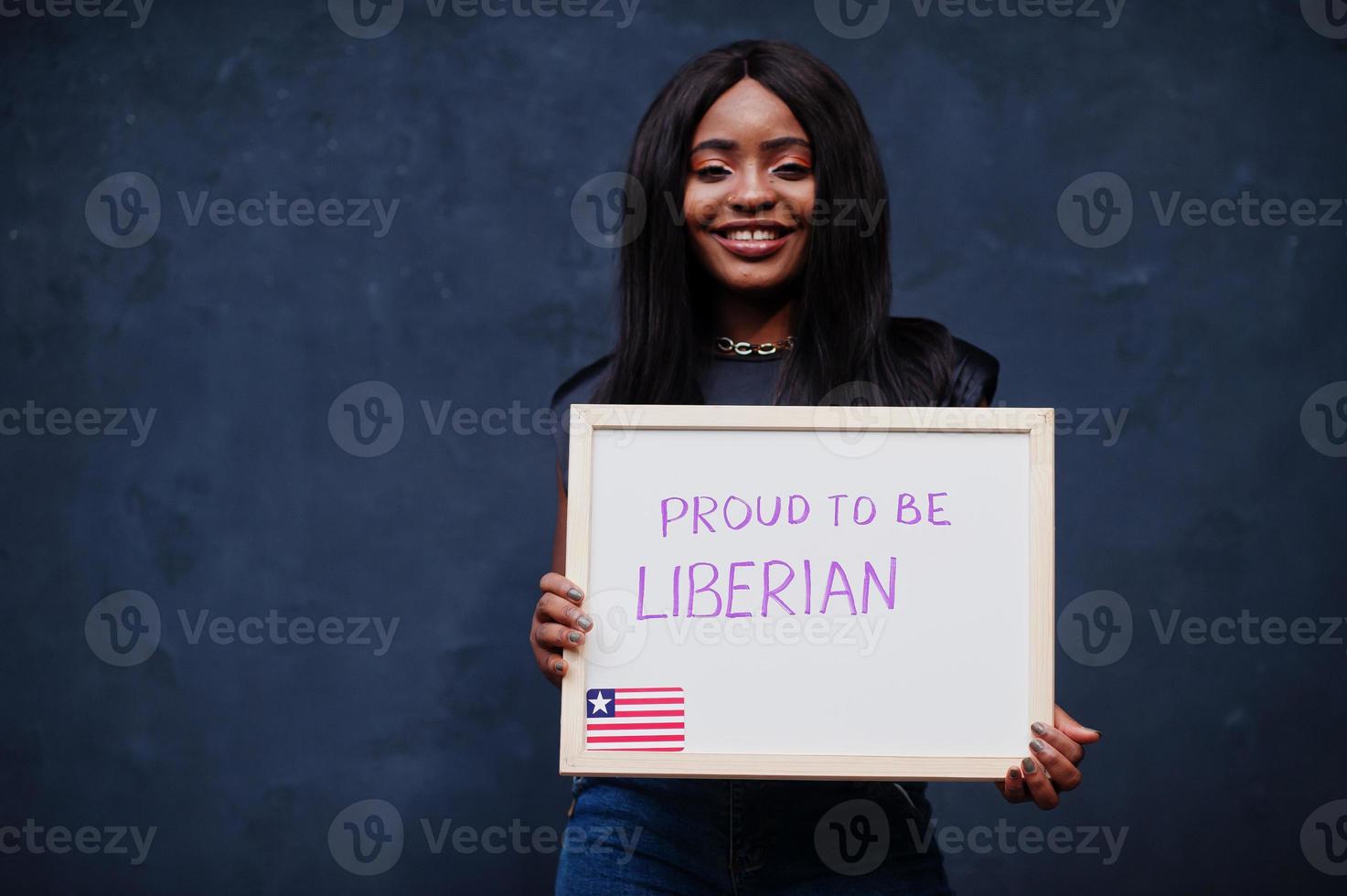 stolt till vara liberian. modern afrikansk kvinna håll styrelse med Liberia flagga. foto