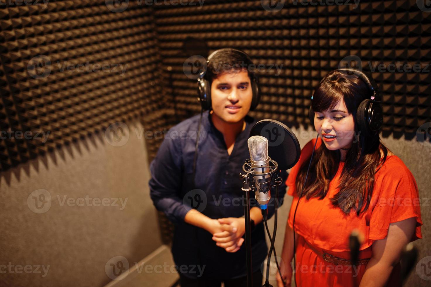 ung asiatisk duett sångare med mikrofon inspelning låt i spela in musik studio. foto