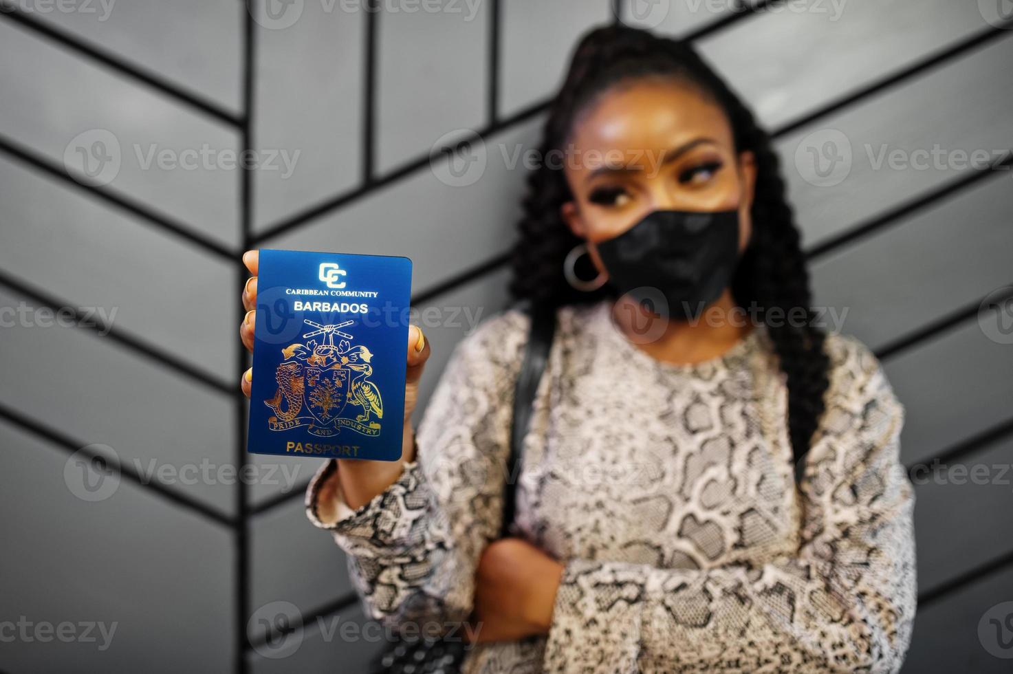 afrikansk amerikan kvinna bär svart ansikte mask visa barbados pass i hand. coronavirus i Amerika Land, gräns stängning och karantän, virus utbrott begrepp. foto