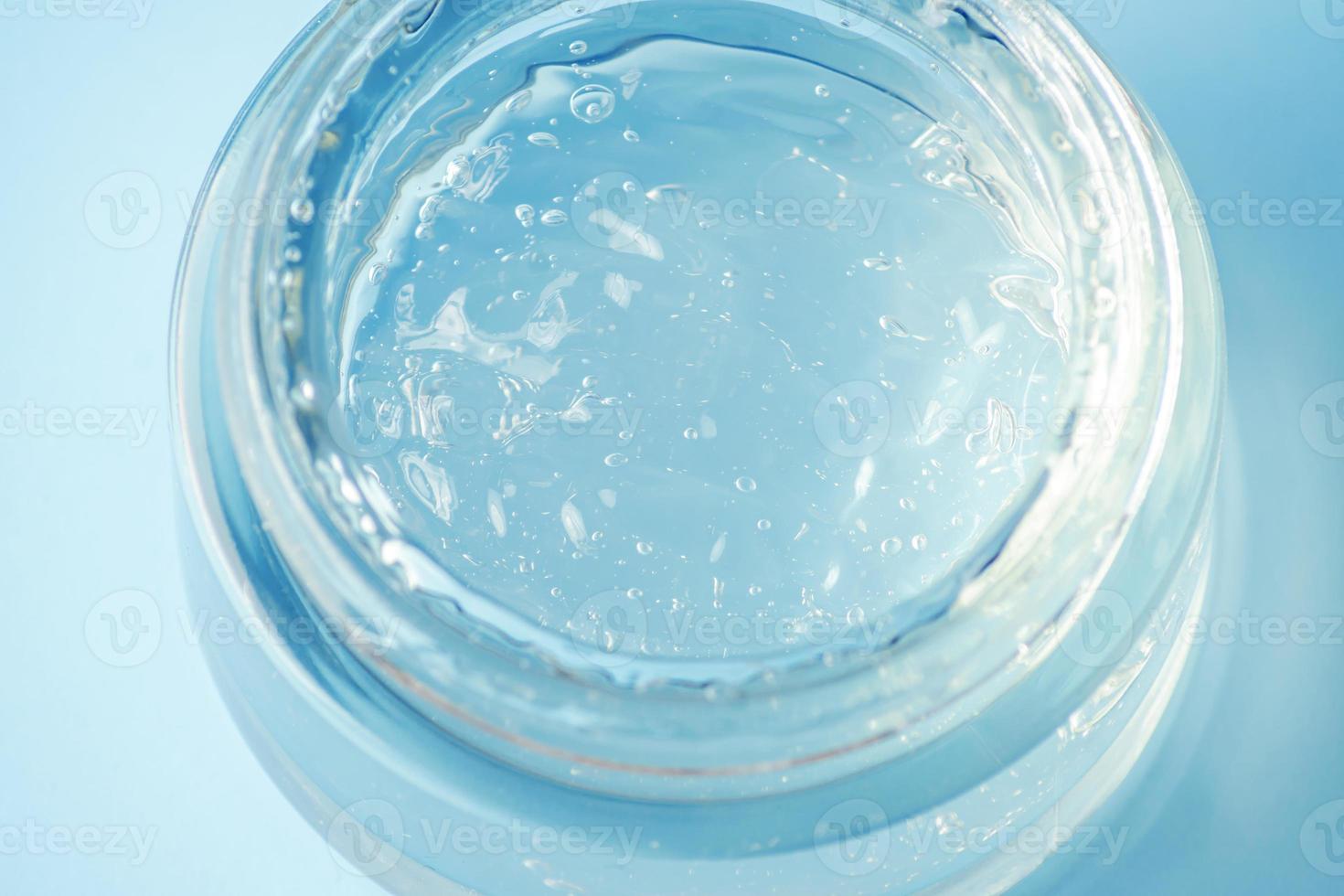 en glas behållare med en t fuktgivande gel på en blå bakgrund. transparent gel med bubblor. foto