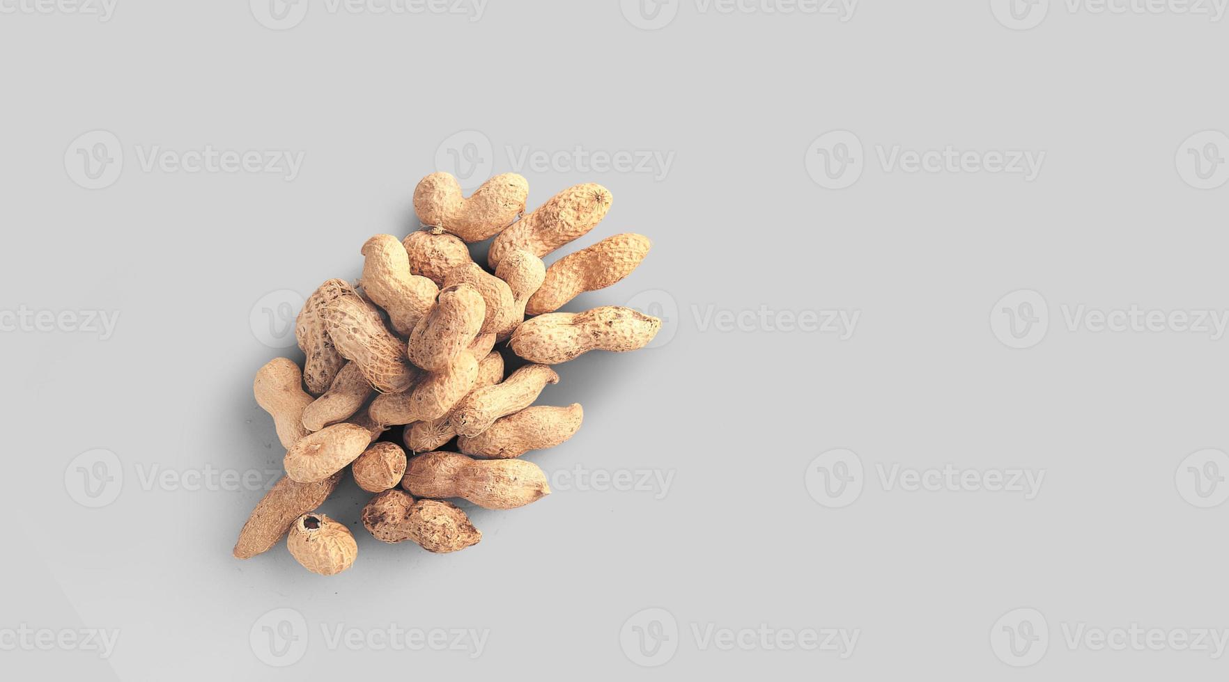 närbild foto av ovanifrån jordnötter, råa jordnötter i nötskal isolerad på grå bakgrund.