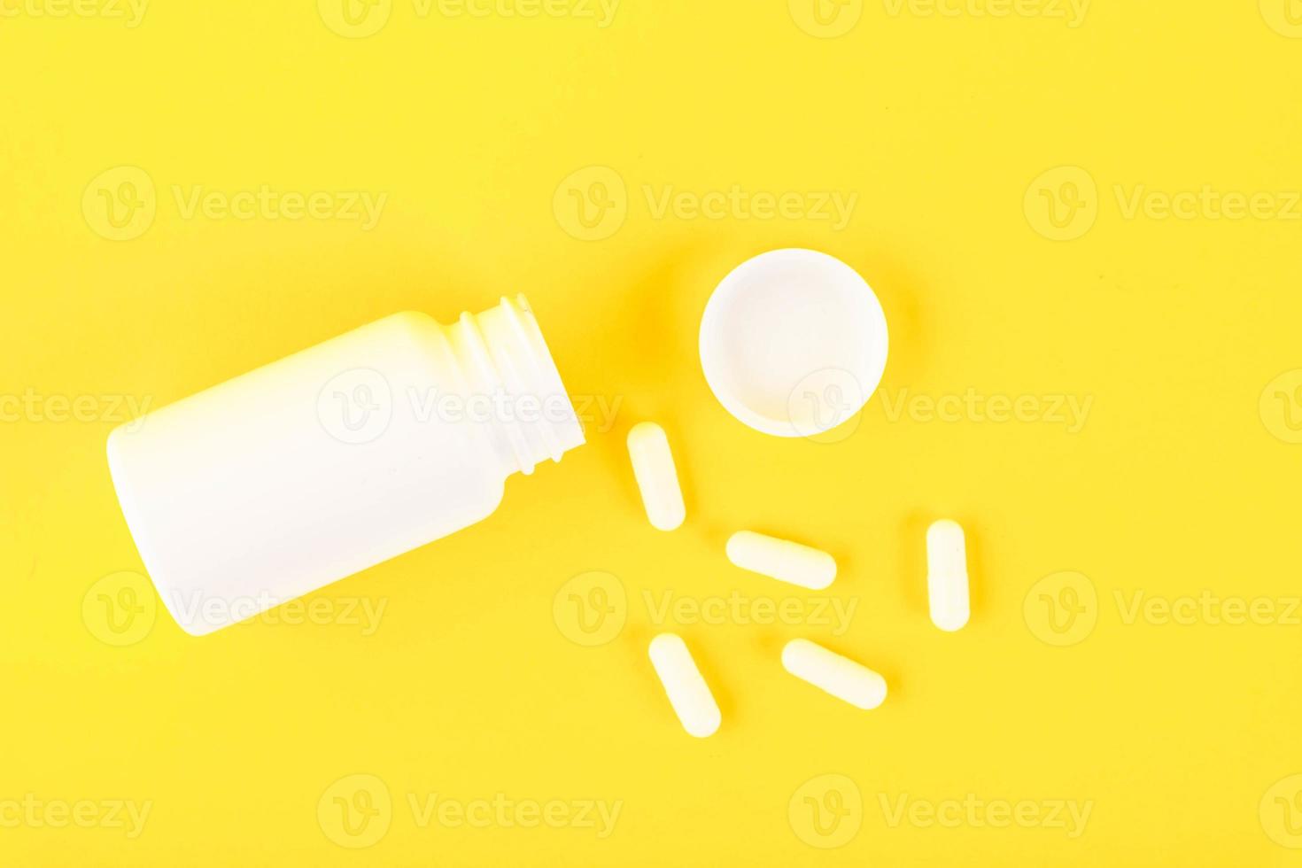 vit plast, medicinsk flaska med biljard, kapslar på en gul bakgrund. kopia Plats foto