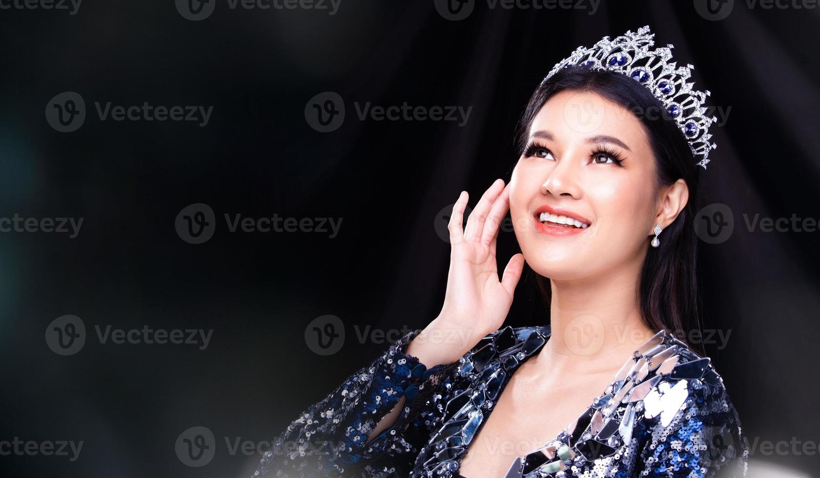 porträtt av Fröken festtåg skönhet tävling i blå paljett kväll boll klänning med gnistra ljus diamant krona, asiatisk kvinna känner Lycklig leende och poser många skillnad stil över mörk rök foto