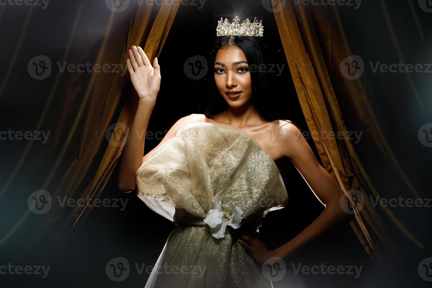 silhuett av Fröken skönhet festtåg tävling kvinna med gnistra diamant krona med solbränd hud skön smink kväll klänning på skede med belysning ridå och mörk bakgrund foto
