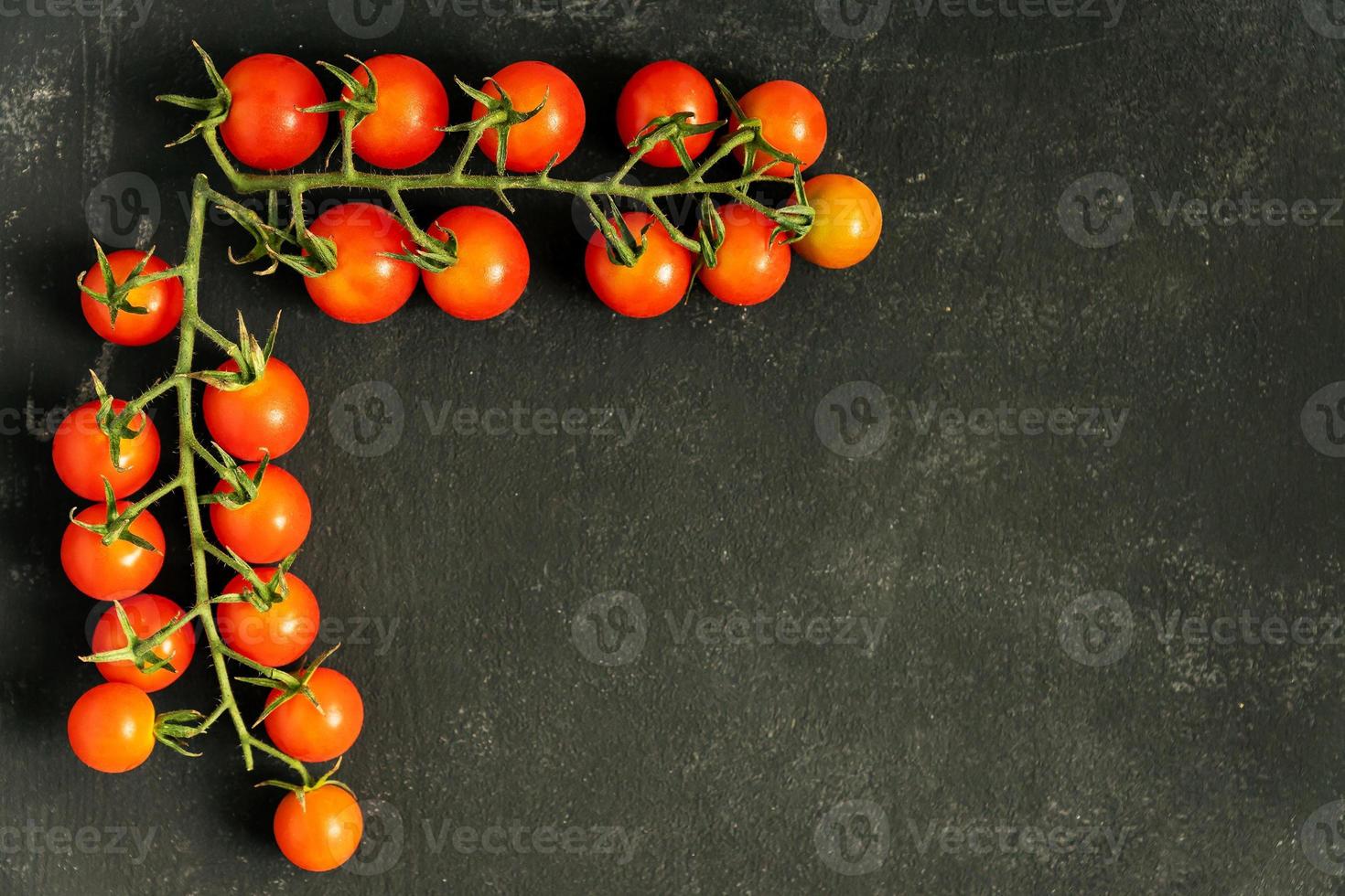 mat ram tillverkad av två grenar av färsk mogen körsbär tomater på svart bakgrund. kopia Plats för din design. foto