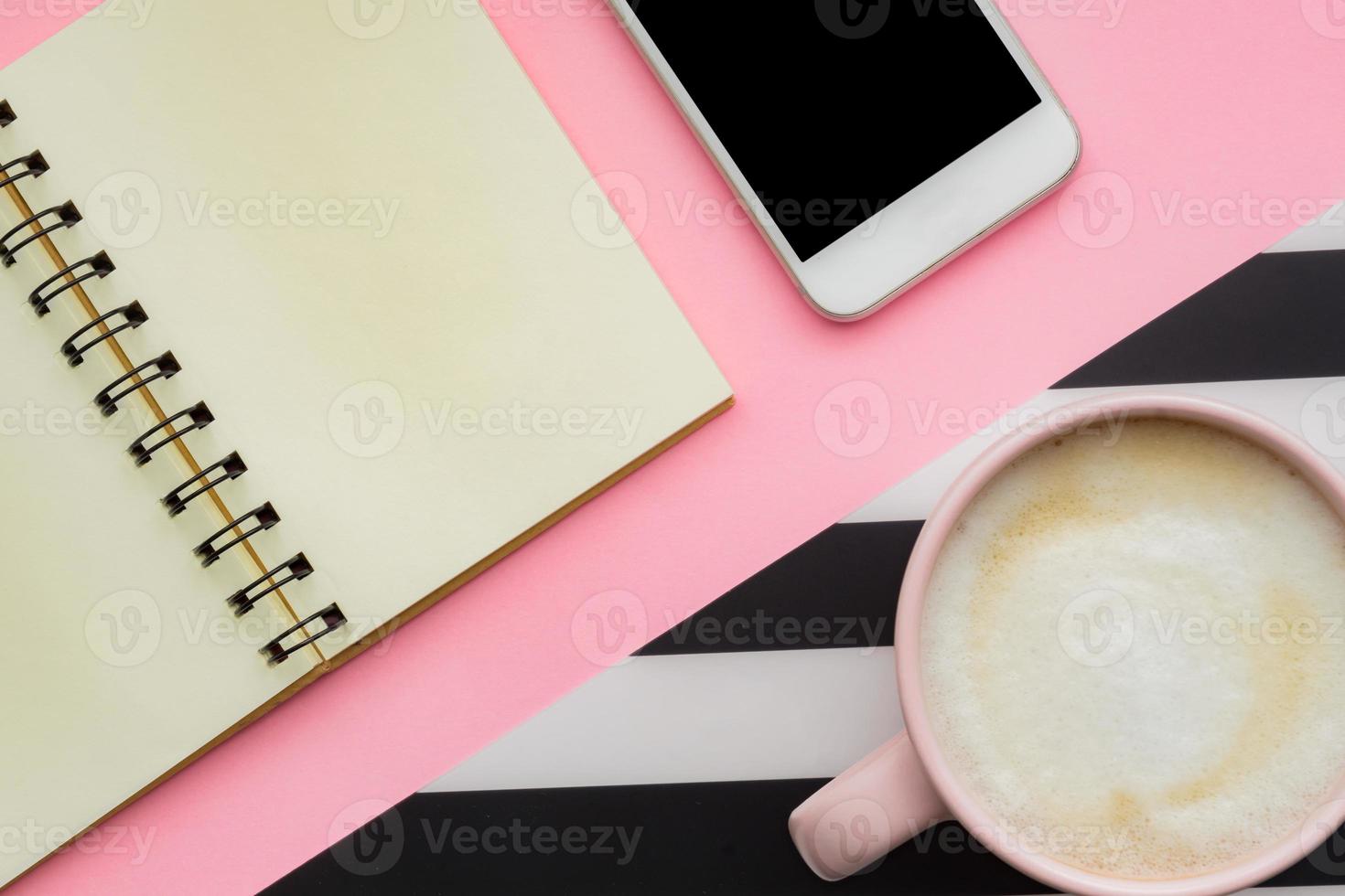 modern vit kontor skrivbord tabell med smartphone och kopp av kaffe. tom anteckningsbok sida för inmatning de text. topp se, platt lägga. foto