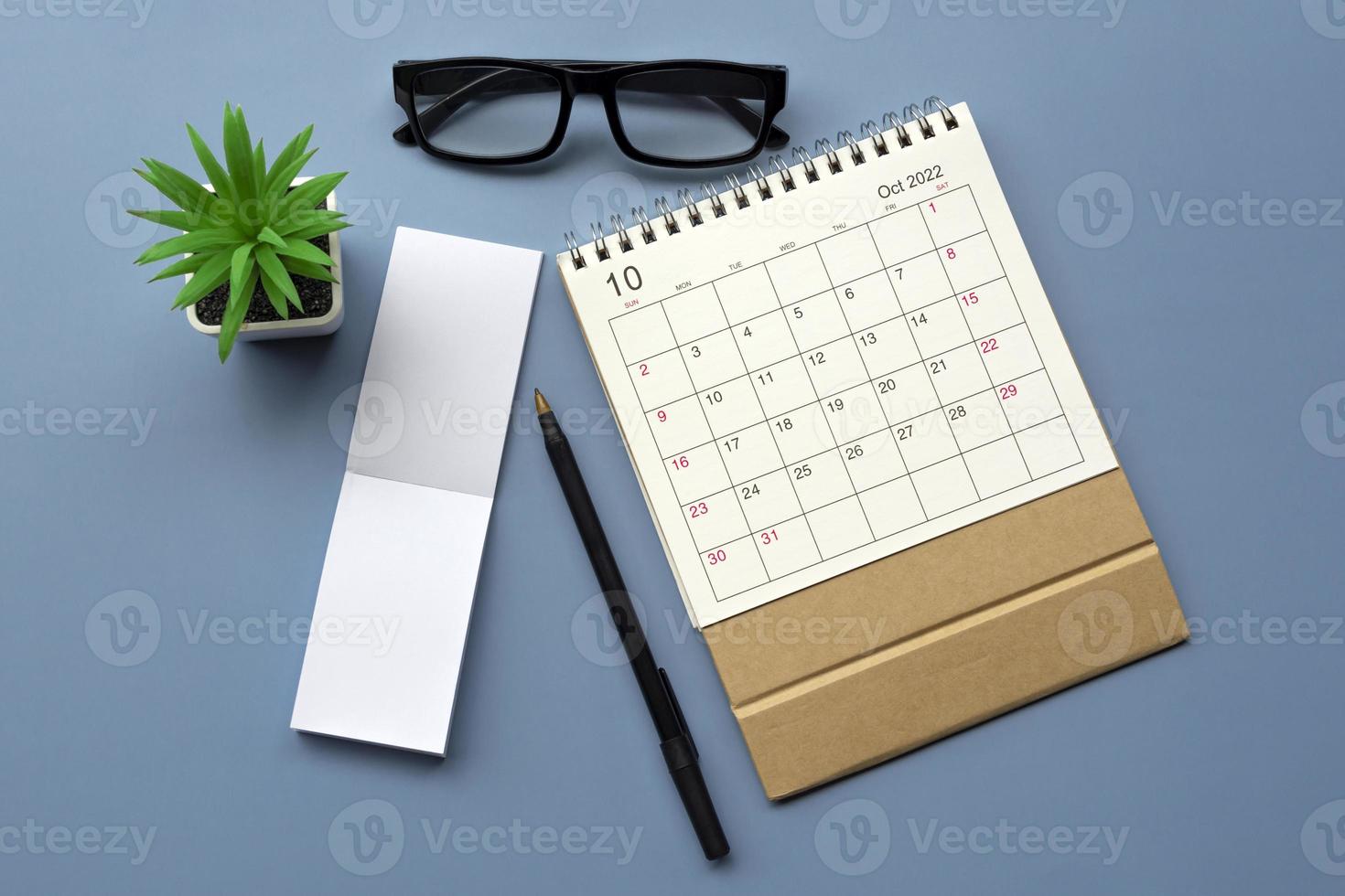 oktober 2022 skrivbord kalender med anteckningsblock på blå bakgrund. kopia Plats. foto