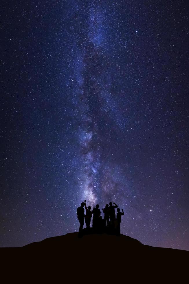 landskap med mjölkig sätt, natt himmel med stjärnor och silhuett av Lycklig människor stående på hög moutain foto