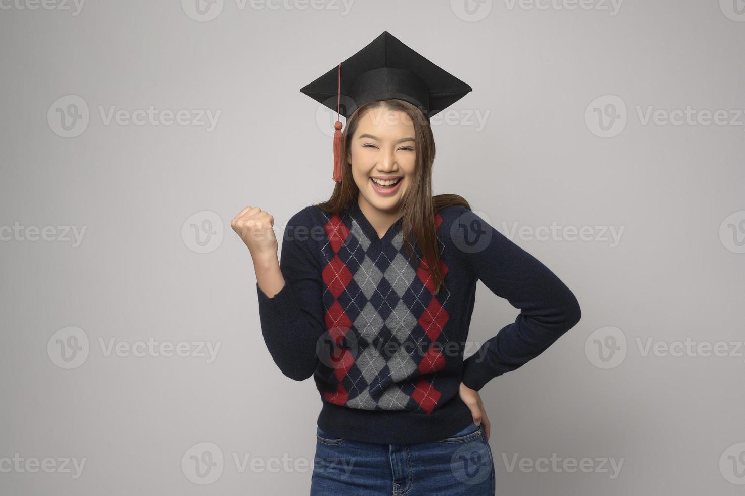 ung leende kvinna innehav gradering hatt, utbildning och universitet begrepp foto