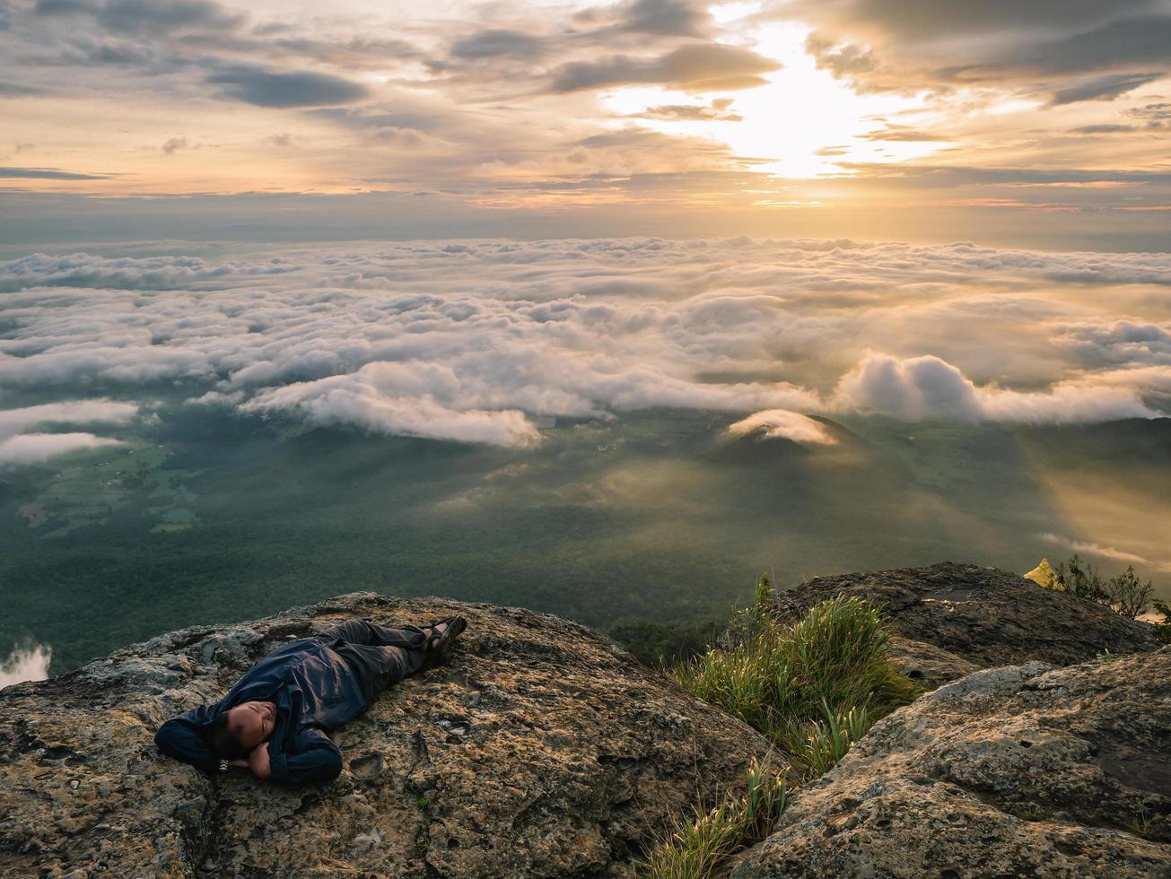 trekker lägga ner på de klippa med skön soluppgång och hav av dimma i de morgon- på khao luang berg i ramkhamhaeng nationell park, sukhothai provins thailand foto