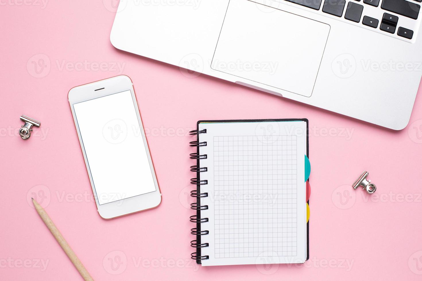mobil telefon, bärbar dator och anteckningsbok i en bur på en rosa bakgrund foto