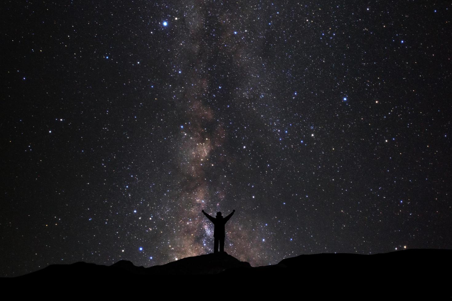 landskap med mjölkig sätt, natt himmel med stjärnor och silhuett av man stående på hög moutain foto