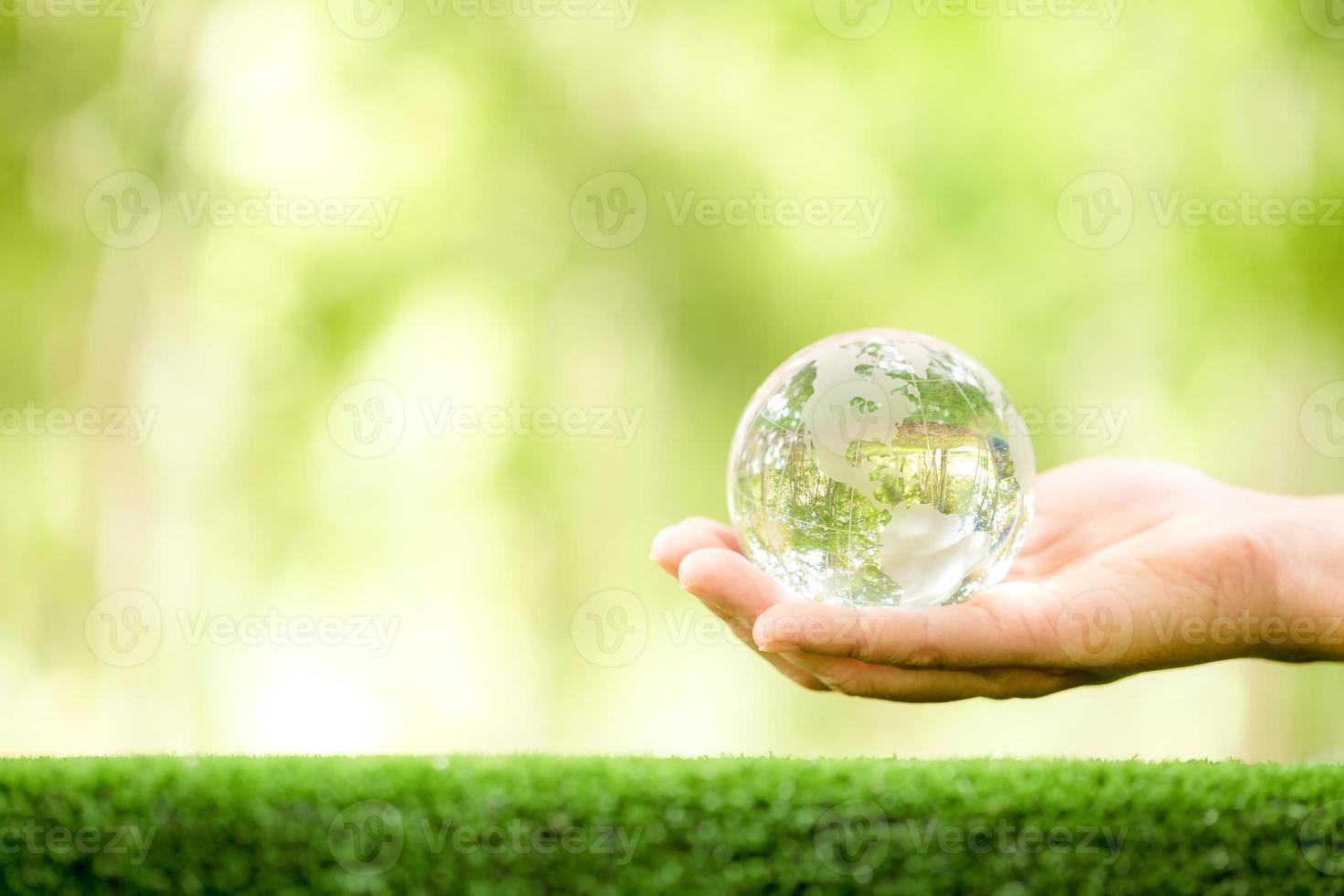 mänsklig hand innehav klot planet glas i grön skog med bokeh natur lampor. värld miljö dag. begrepp för miljö bevarande, skydda ekologi jord och miljö- miljövänlig liv. foto