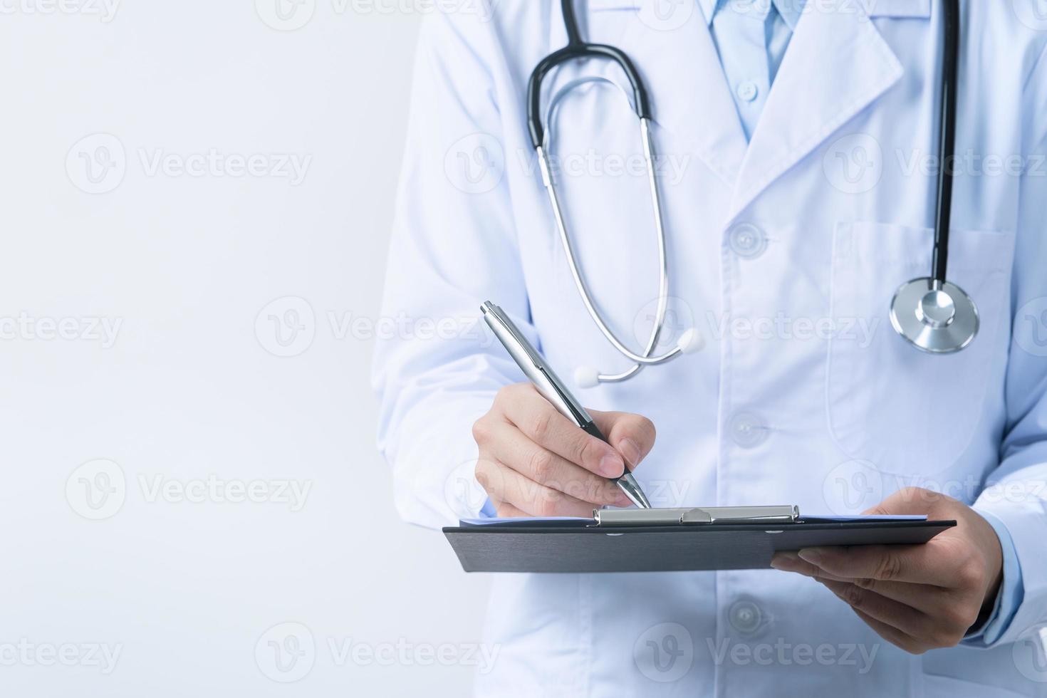 läkare med stetoskop i vit täcka innehav urklipp, skrivning medicinsk spela in diagnos, isolerat på vit bakgrund, stänga upp, beskurna se. foto