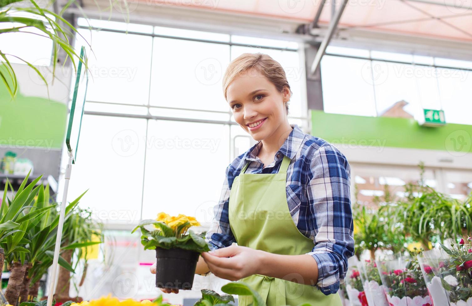 glad kvinna med blommor i växthus foto