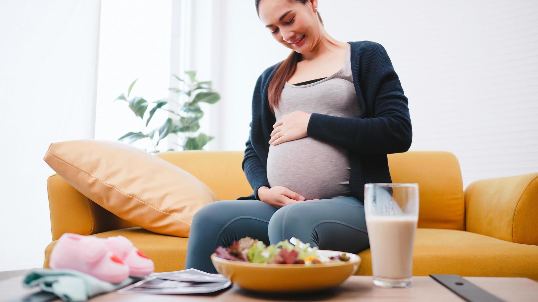 Lycklig gravid kvinna äter friska mat för henne ofödd bebis. foto