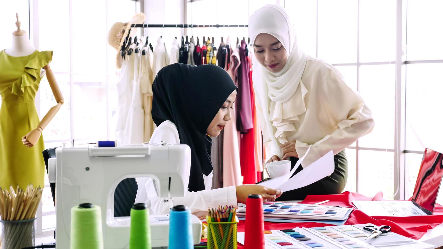 skön muslim kvinnor arbetssätt tillsammans på de Kläder kontor. foto