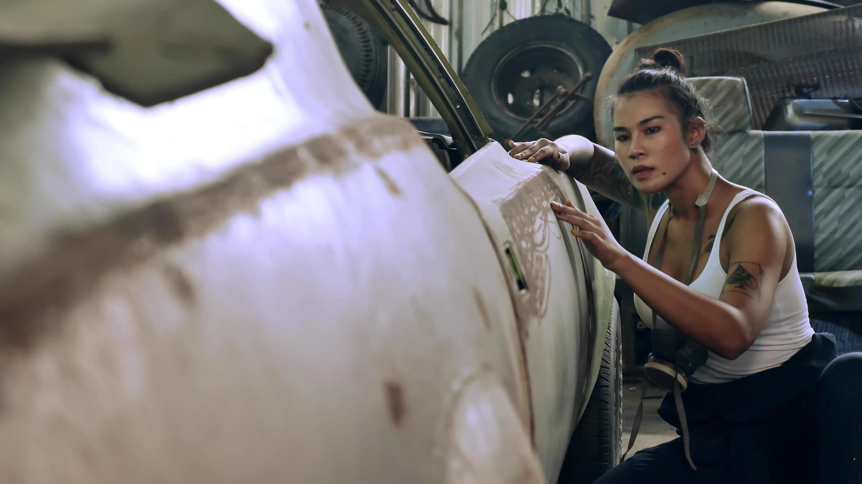 attraktiv ung kvinna mekanisk arbetstagare reparation en årgång bil i gammal garage. foto