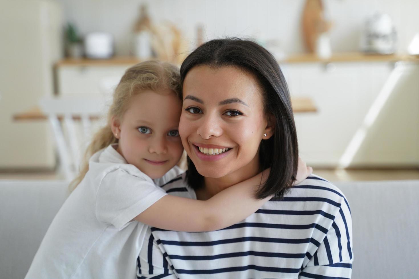 porträtt av mamma och söt liten flicka. blond unge kramar mamma. stilig kvinna och flicka tillsammans på Hem. foto