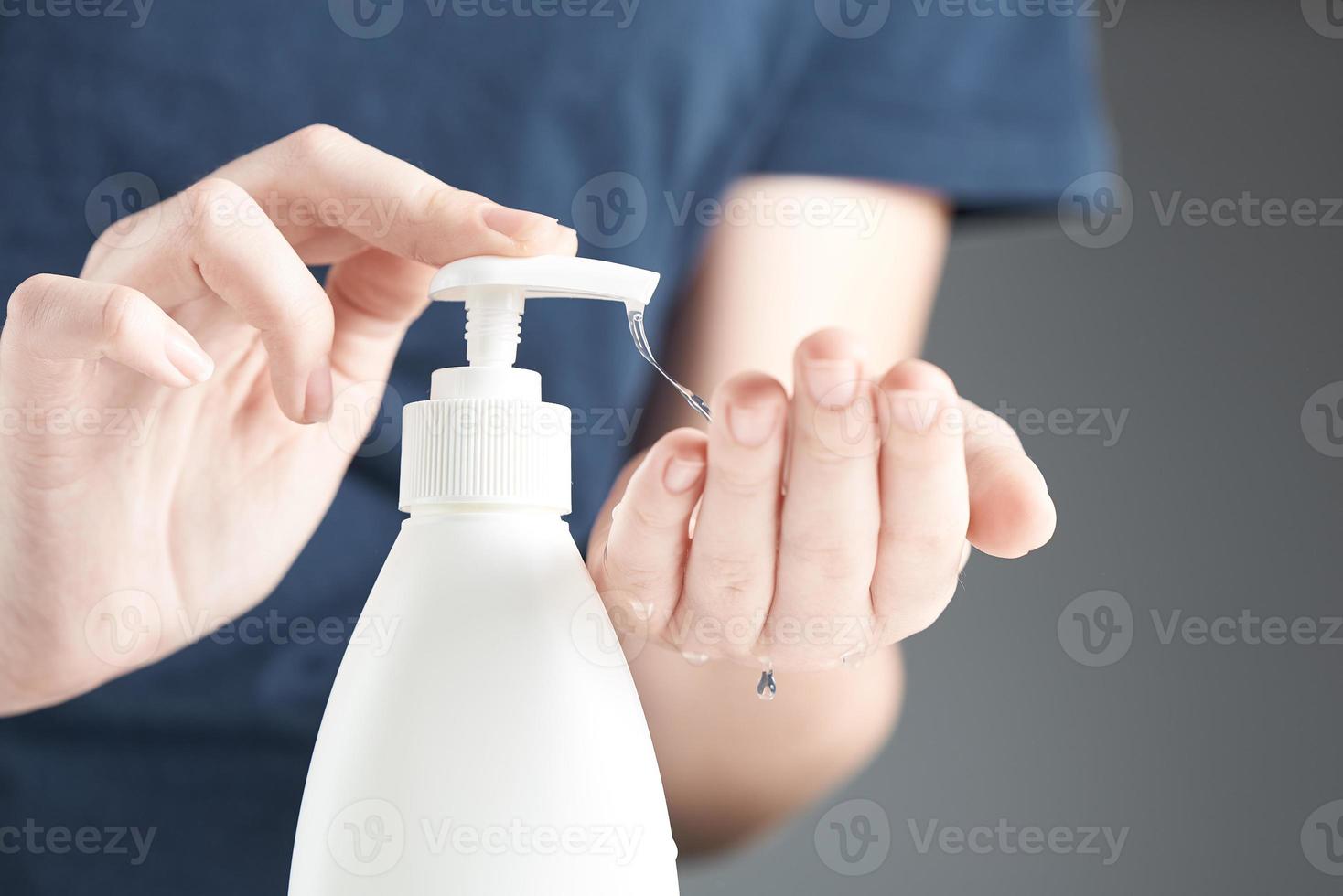 kvinna händer använder sig av hand desinfektionsmedel gel pump dispenser. en ström av klar gel droppar ner från hand. foto