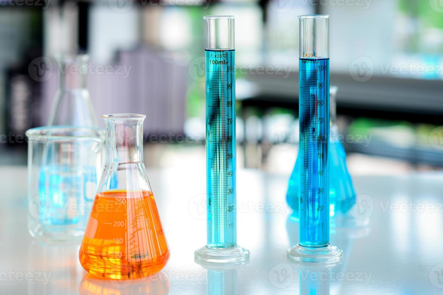 orange kemikalier i flaska och blå kemikalier i cylinder rör placerad på de tabell var beredd för kemisk experiment i kemisk laboratorier. foto