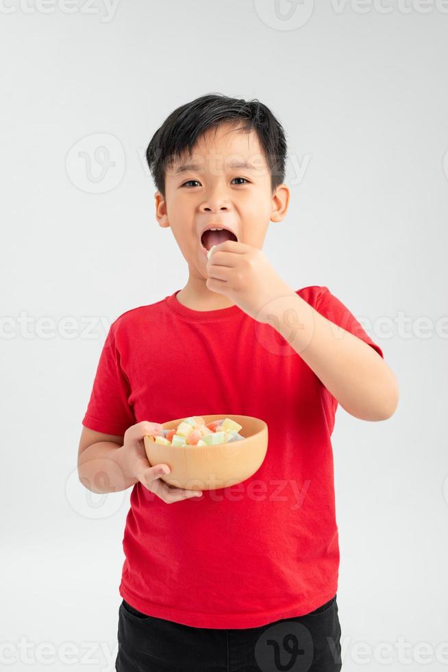 pojke äter en gelé bebis från en skål av blandad färgad lollies godis. foto
