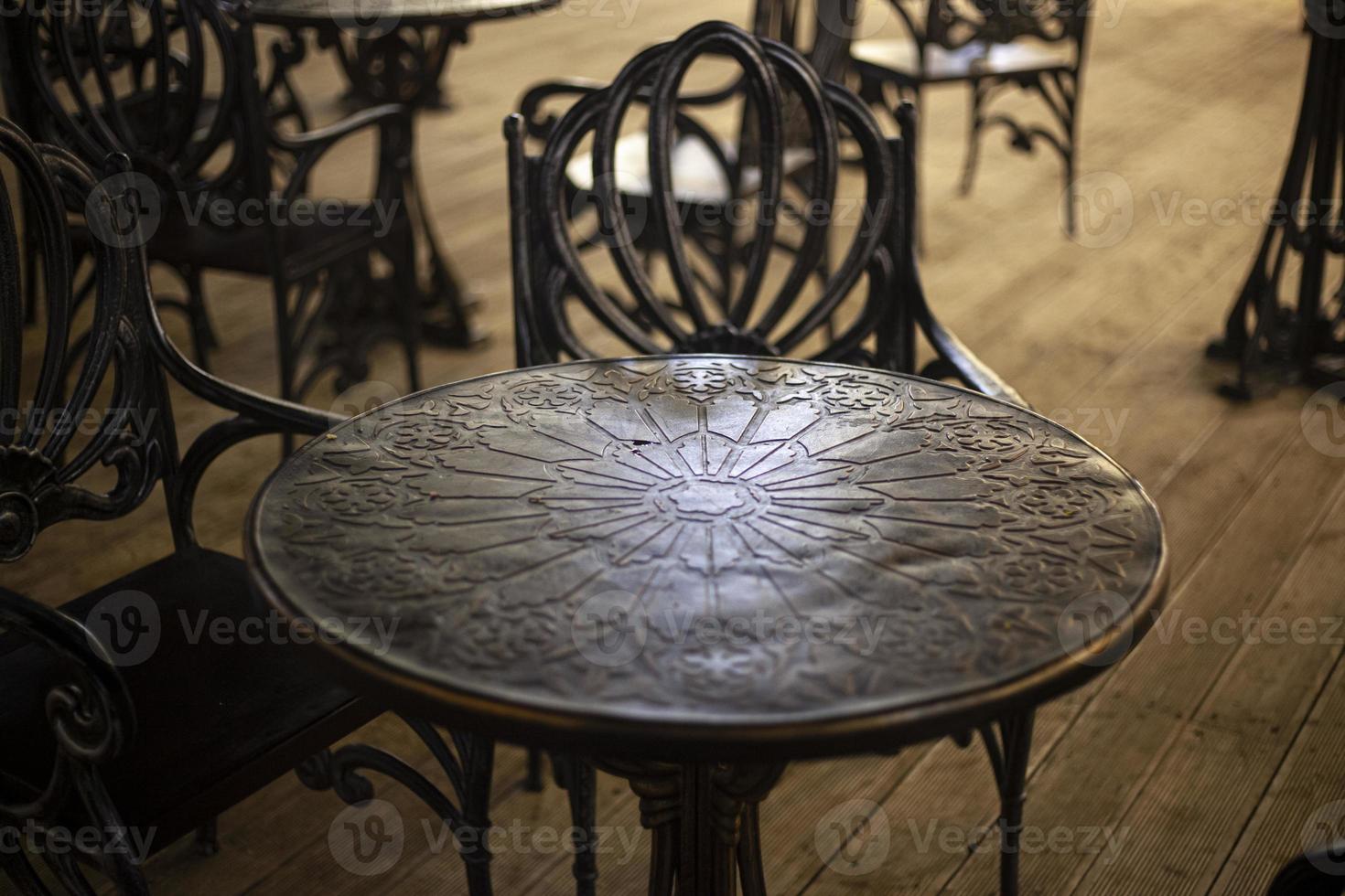 monolitisk tabell tillverkad av metall. smidda möbel för ett utomhus- Kafé. dining plats i de stad. skön metall möbel tabell och stolar. en bit av interiör. foto