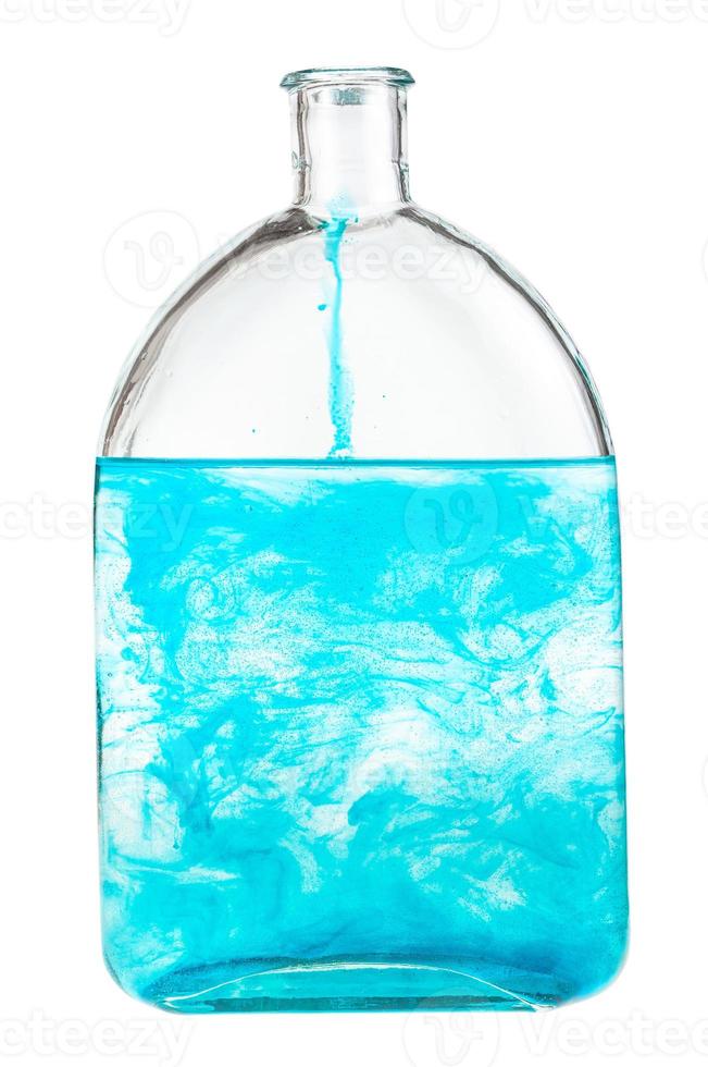 blå färga upplöses i vatten i flaska isolerat foto