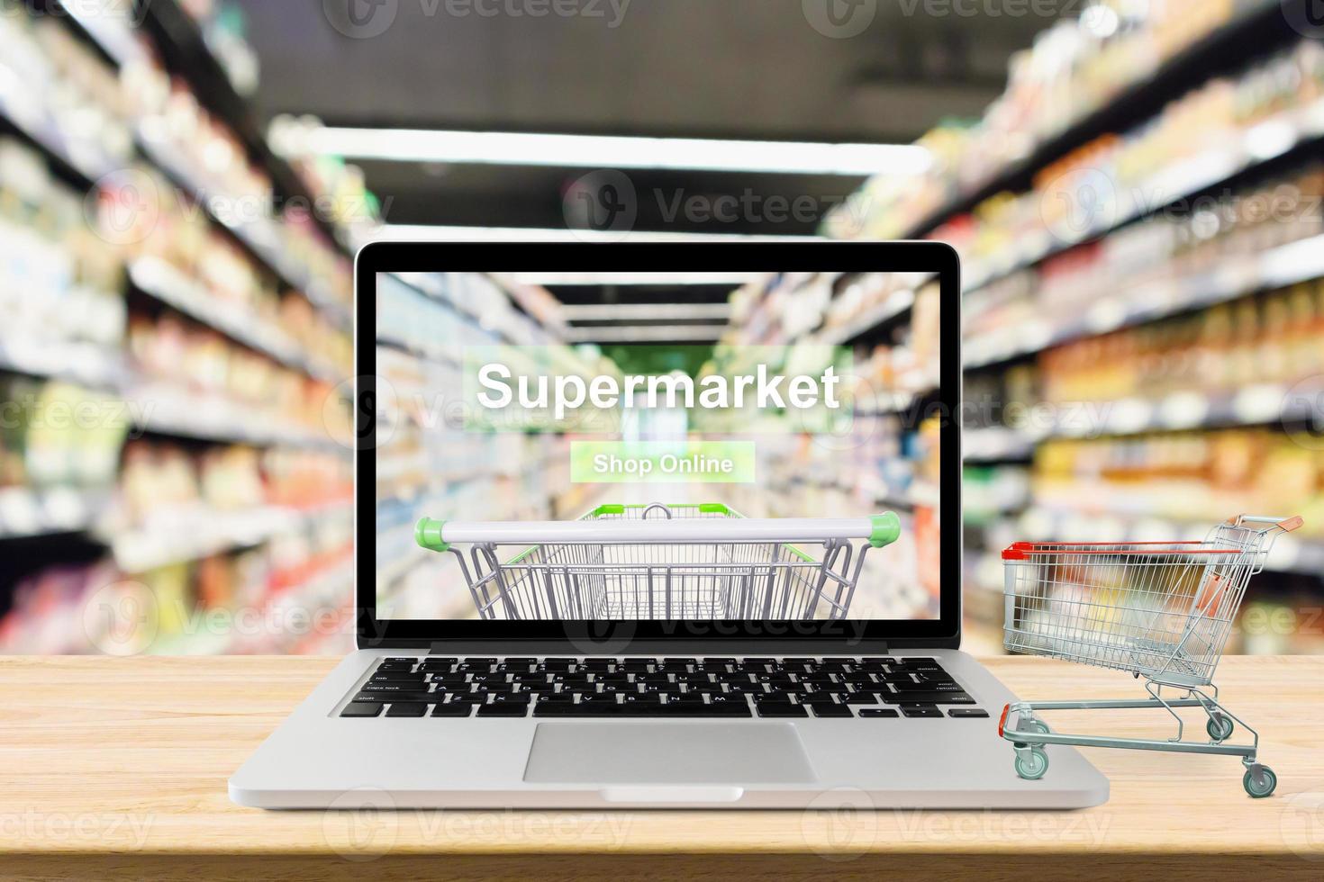 bärbar dator på träbord med supermarket gång suddig bakgrund online shopping koncept foto