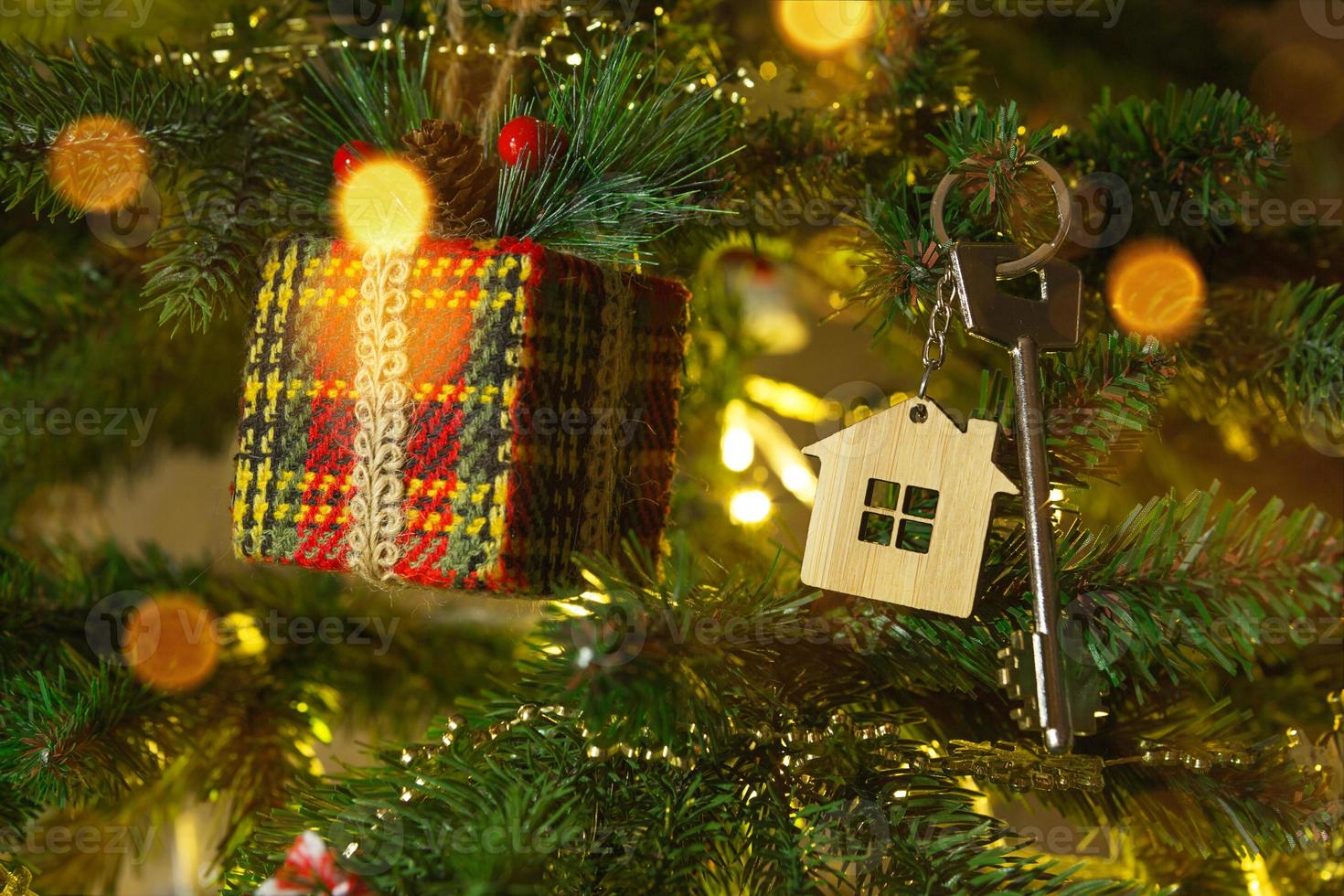 nyckeln till huset med en nyckelring hänger på julgranen. en present till nyår, jul. bygga, designa, projektera, flytta till nytt hus, belåna, hyra och köpa fastigheter. kopieringsutrymme foto