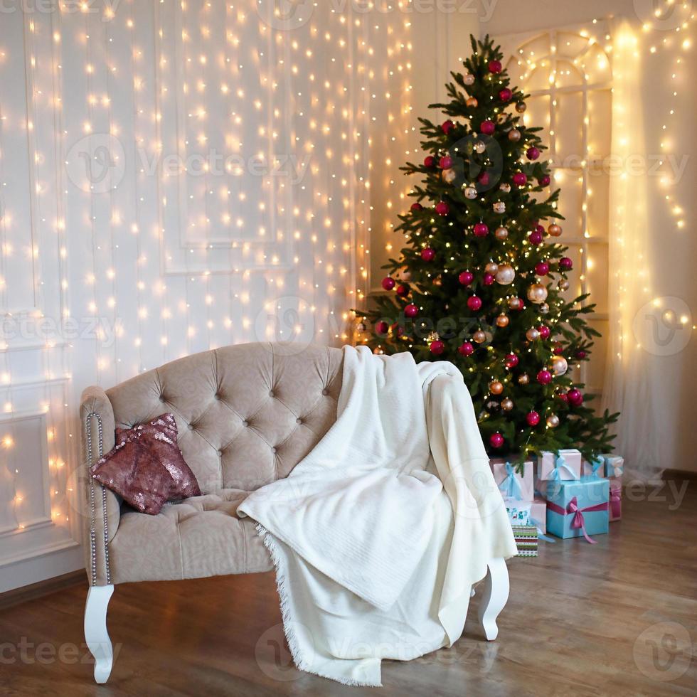 dekorerad julgran i vardagsrummet med soffa, filt, ljus girlander. sovrum med en säng. nytt år, jul foto