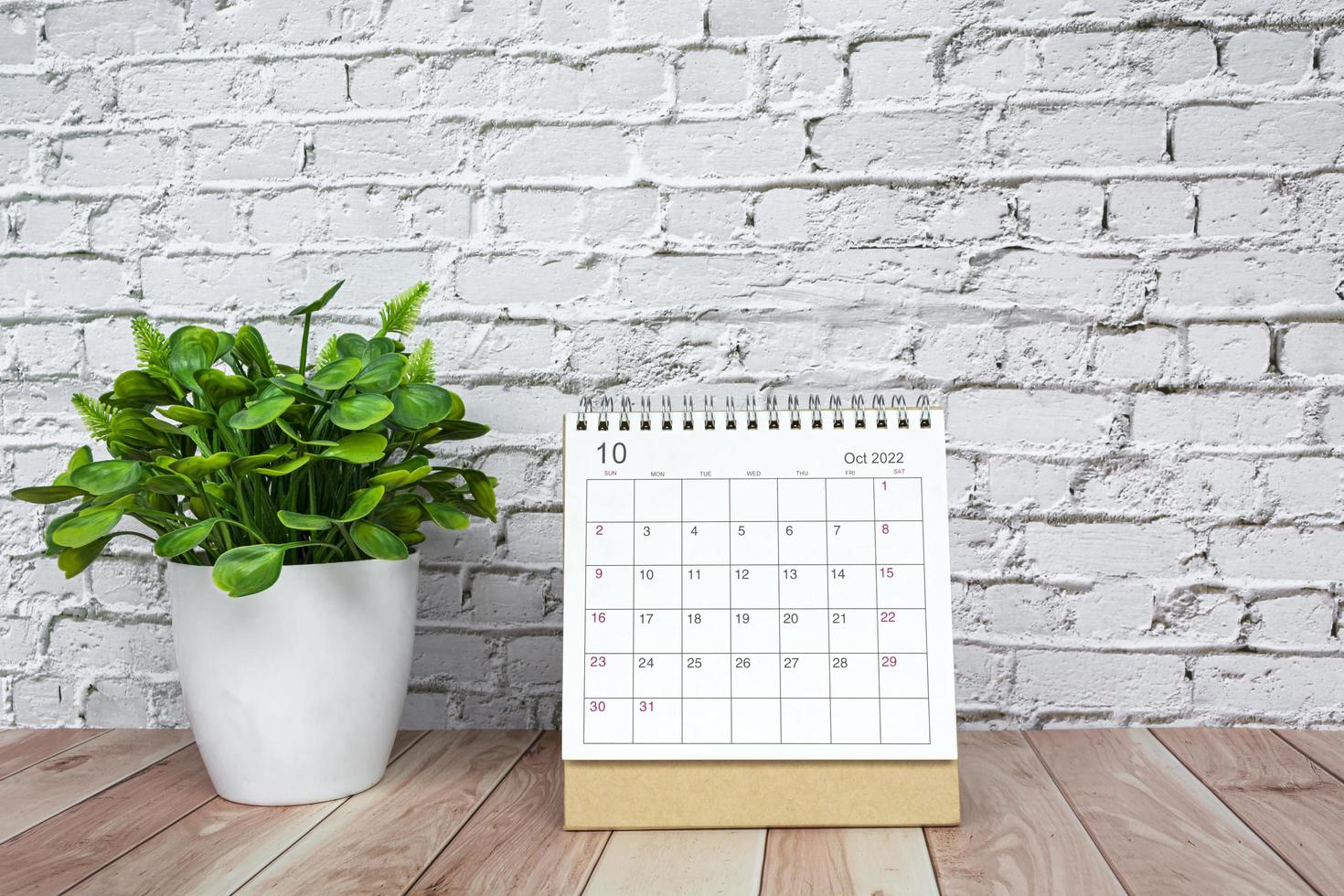 oktober 2022 vit kalender med inlagd växt på trä- skrivbord foto