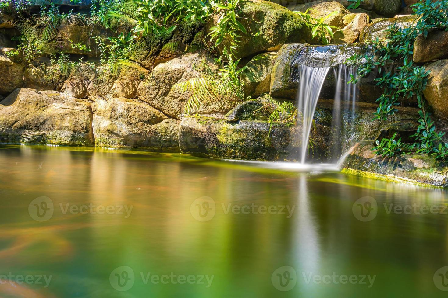 japansk trädgård vattenfall. frodig grön tropisk koi damm med vattenfall från varje sida. en frodig grön trädgård med vattenfall cascading ner de klippig stenar. zen och fredlig bakgrund. foto
