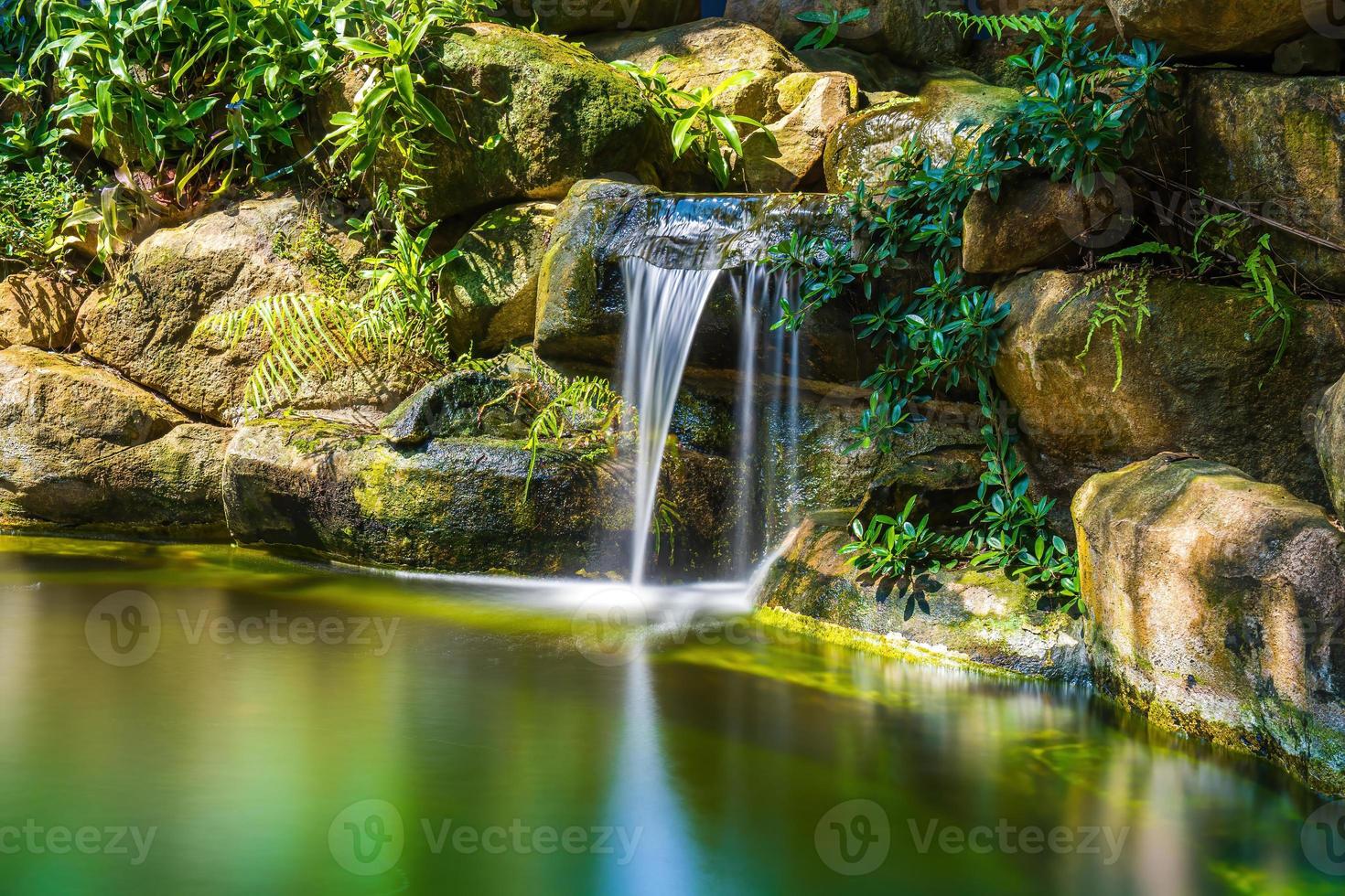 japansk trädgård vattenfall. frodig grön tropisk koi damm med vattenfall från varje sida. en frodig grön trädgård med vattenfall cascading ner de klippig stenar. zen och fredlig bakgrund. foto