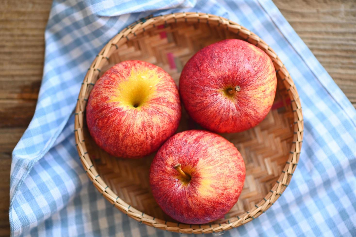 äpple frukt på korg på de trä- tabell, mogen röd äpplen foto