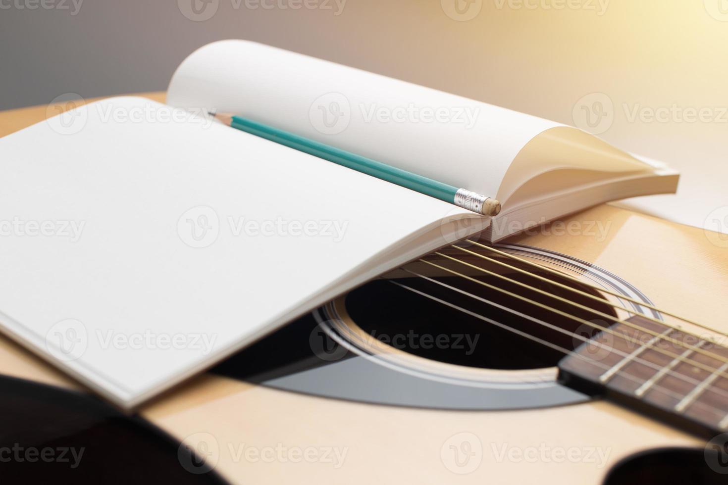 komponera musik. penna och anteckningsbok placerad på akustisk gitarr foto