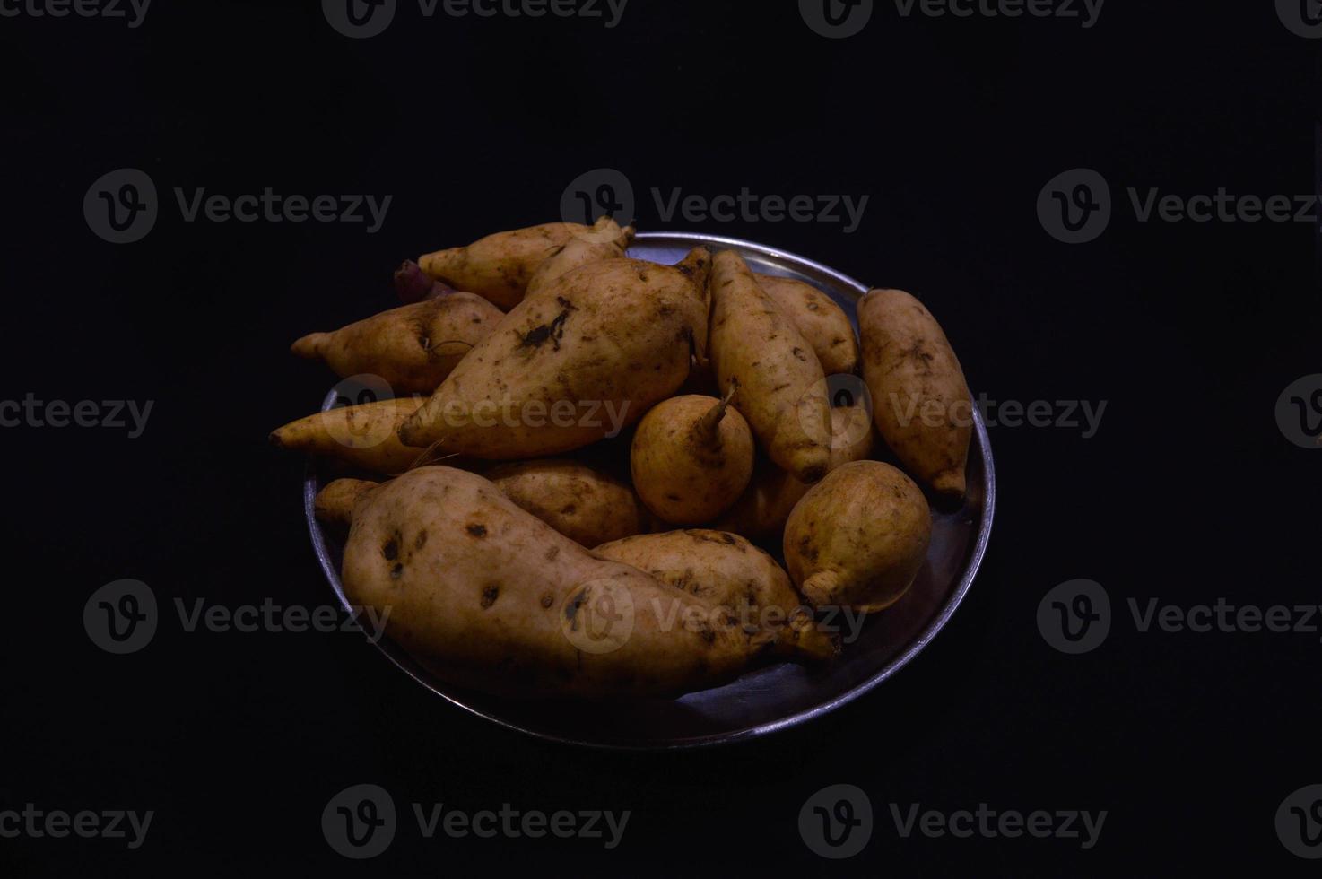 ljuv potatis på en tallrik på en svart bakgrund foto