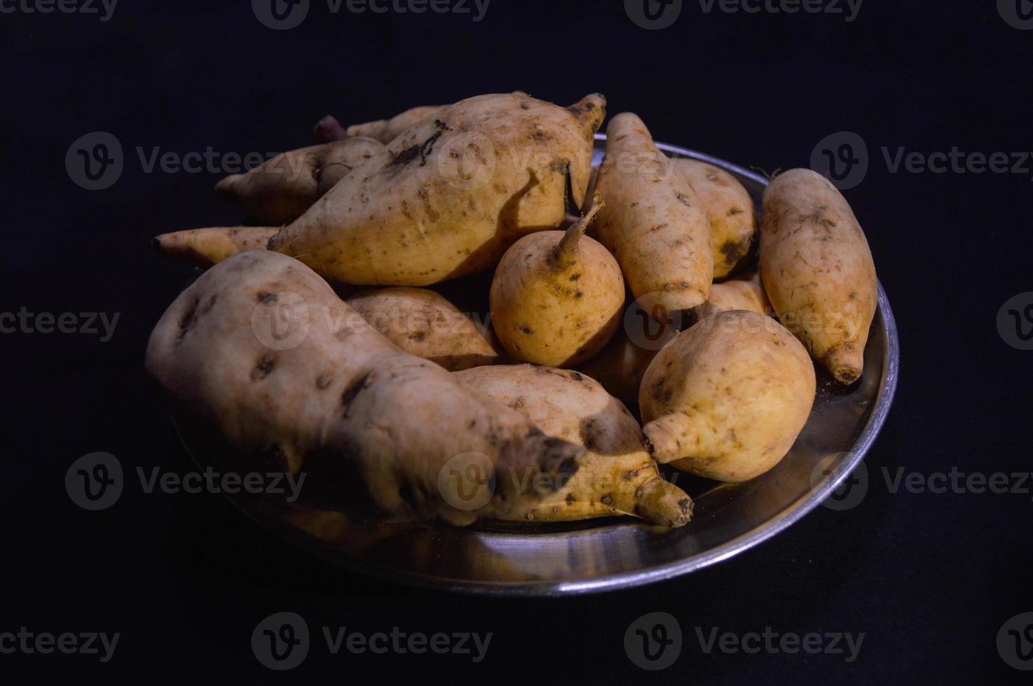 ljuv potatis på en tallrik på en svart bakgrund foto