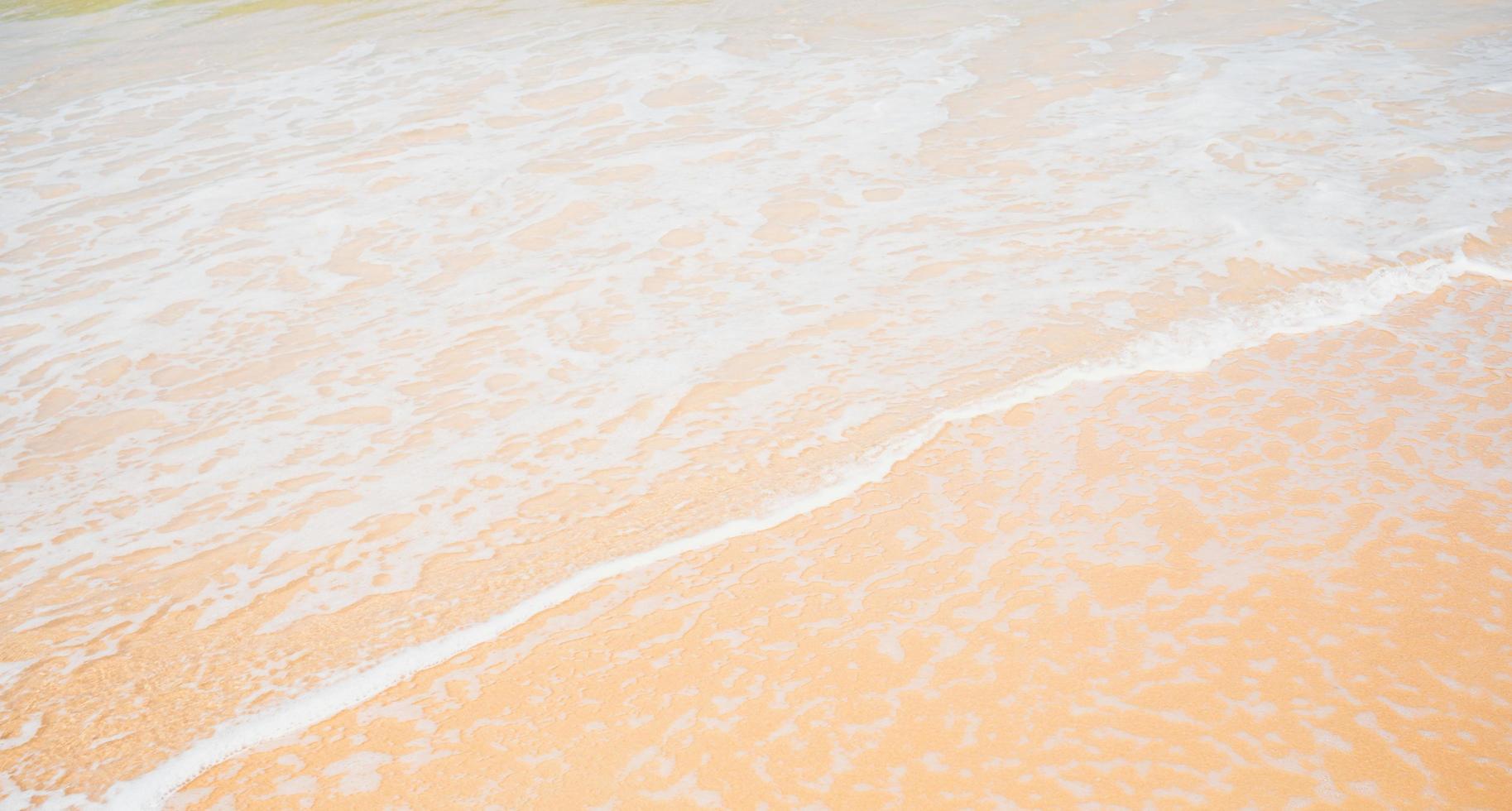 närbild gyllene sandig vågor vatten stänk strandlinje. foto