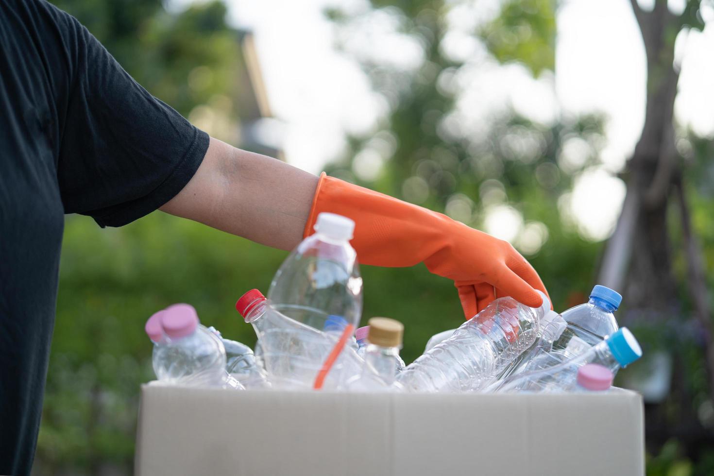 asiatisk kvinna volontär bär vatten plastflaskor i soplåda papperskorgen i parken, återvinna avfall miljö ekologi koncept. foto