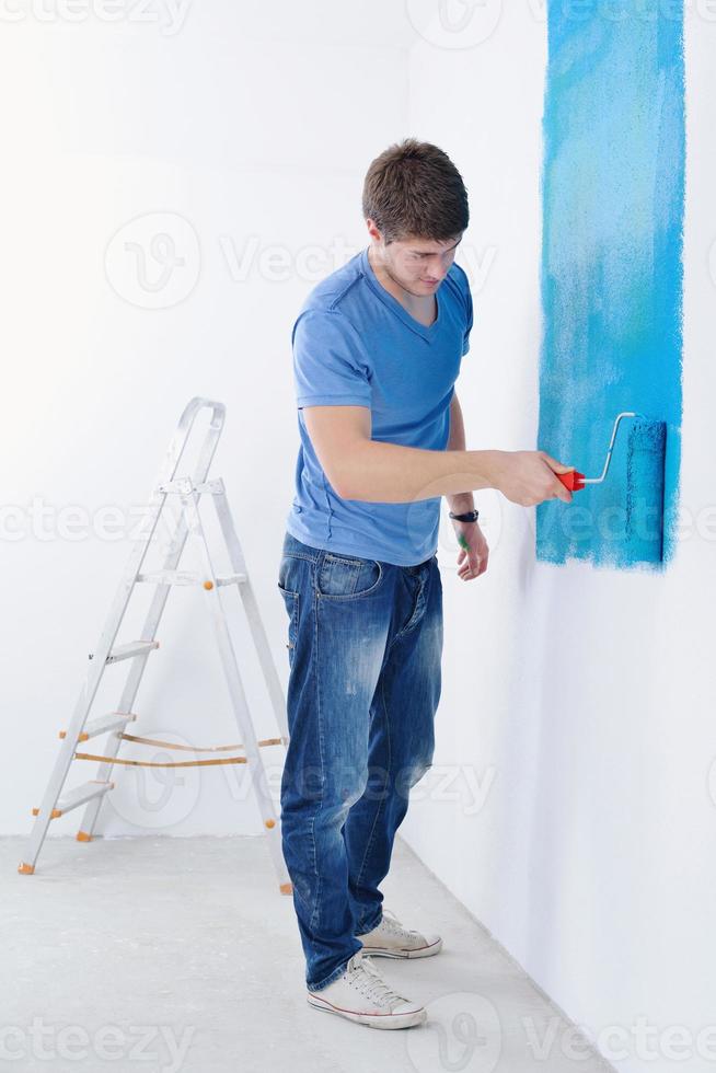 stilig ung man måla vit vägg i Färg foto