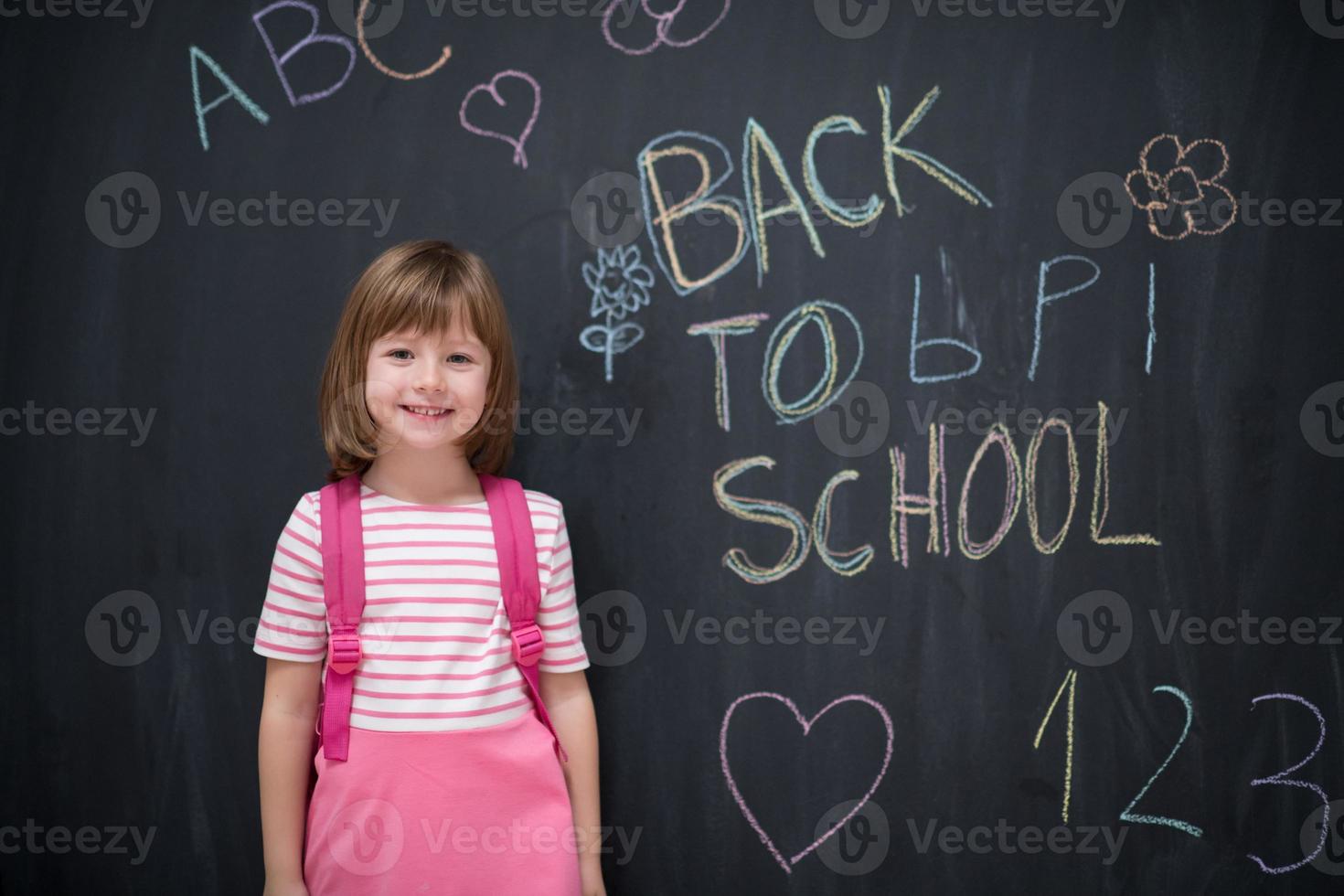 skola flicka barn med ryggsäck skrivning svarta tavlan foto