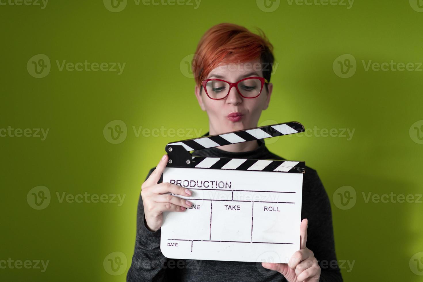 rödhårig kvinna innehav film kläpp på grön bakgrund foto