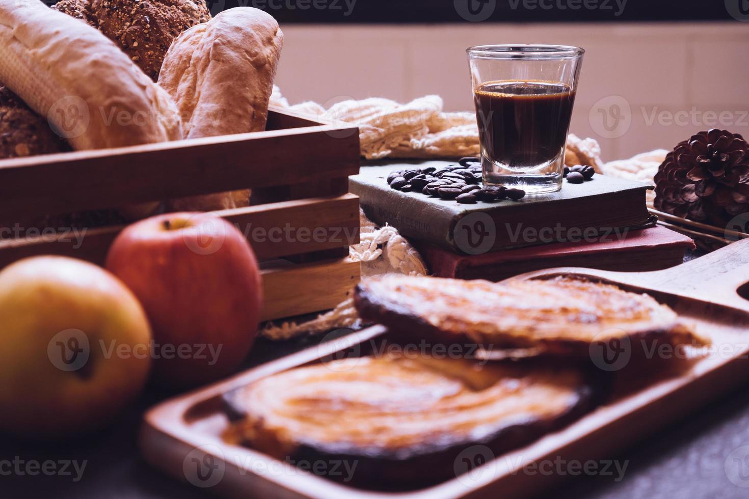 bakad bröd, äpplen och kaffe på en tabell. foto