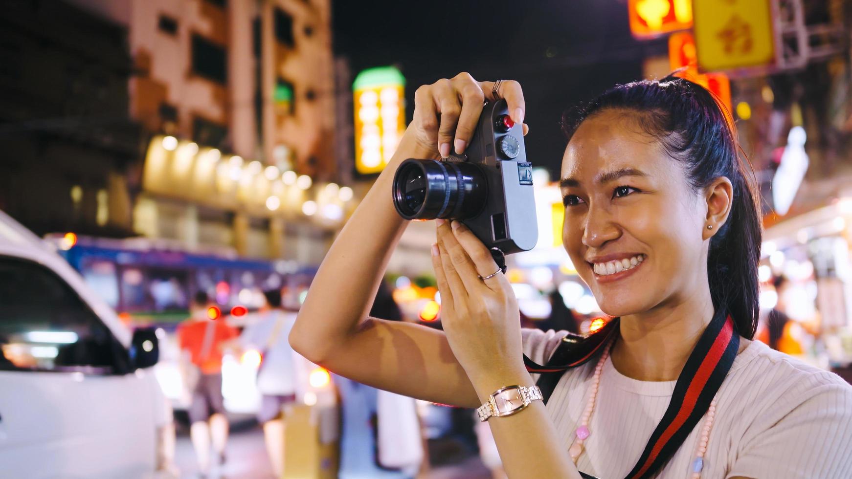 ett asiatisk kvinna turist åtnjuter tar foton av de natt se av Yaowarat väg eller china i Bangkok, thailand.